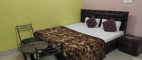 Un dormitorio con cama, una silla, una mesita de noche y una pequeña mesa.