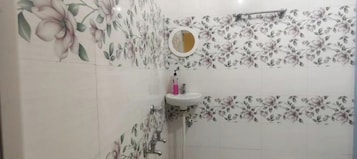 Um banheiro com papel de parede floral, pia com espelho e área de chuveiro.