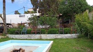 A pool with a fire pit, surrounded by a low stone wall and various chairs. - The Maison Bleu room (TANGER)