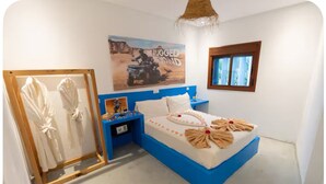 A bedroom with a blue bed, a framed artwork, a nightstand, and a window. - The Maison Bleu room (TANGER)