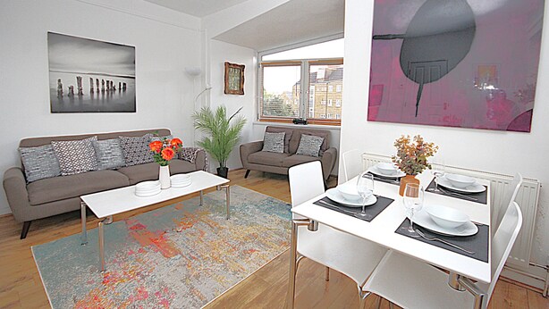 A modern living room with a dining area, featuring a sofa, coffee table, and dining table set for four. - Boutique Apartment minutes to London Bridge Tube (London)