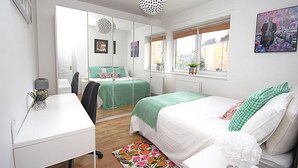 A bedroom with a bed, a desk, a chair, a mirror, and a window with a view of buildings. - Boutique Apartment minutes to London Bridge Tube (London)