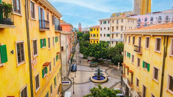 A narrow street lined with yellow buildings, a central fountain, and a distant tower. - La Maison De Dino Hotels & Apartments  (Phu Quoc)