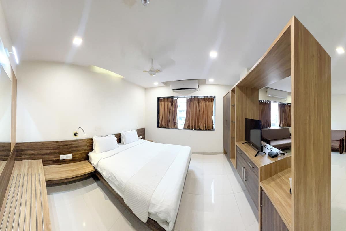 A modern hotel room with a bed, bedside tables, a TV, and a desk area.
