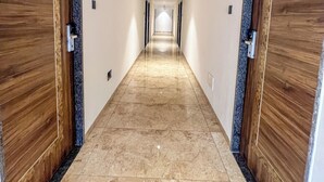 A hallway with wooden doors and marble flooring. - THE GRAND KD HOTEL (Dabhoi)