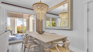 Un espace repas avec une grande table, des chaises en osier et un lustre.