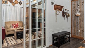 Ein Zimmer mit einer Schiebetür, einem Sofa, einer Bank und Körben an der Wand.