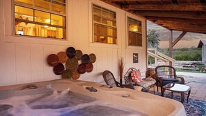 Ein Whirlpool mit Holzboden, eine Wand mit dekorativen Tellern und eine Terrasse mit Stühlen und einem Teppich.
