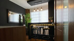 Un interior moderno con zona de bar, asientos y piso cubierto de alfombra verde.