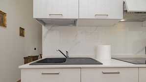 A modern kitchen with a built-in sink, white cabinetry, and a marble backsplash.