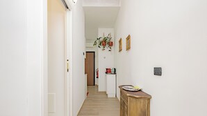 A hallway with a wooden cabinet, a door, and a wall-mounted light switch.