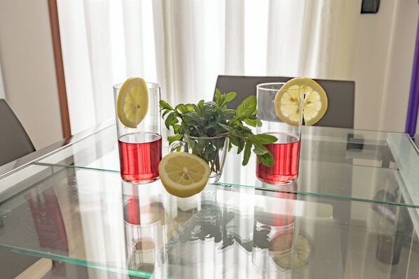 A glass table with two red glasses, a lemon slice, and a small potted plant.