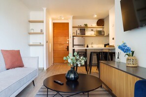 A modern living room with a sofa, a coffee table with a vase, and a remote control.