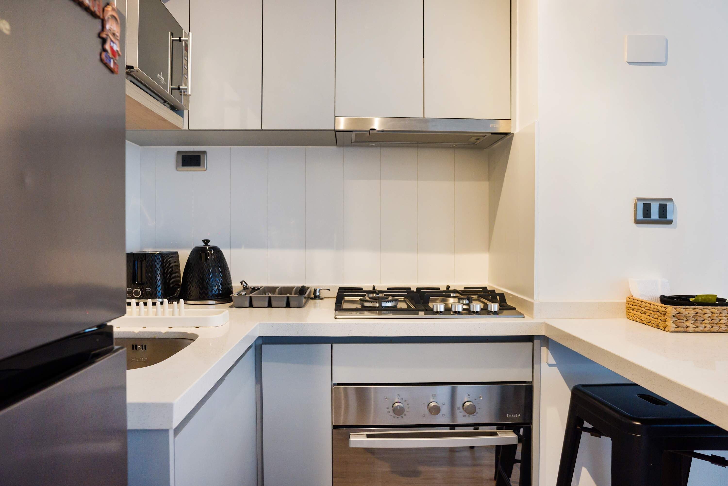 A modern kitchen with white cabinetry, a stainless steel range hood, a gas stove, and a built-in oven.