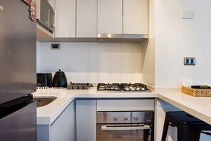 Une cuisine moderne avec des meubles blancs, une hotte en acier inoxydable, une cuisinière à gaz et un four encastré.