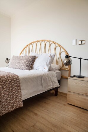A bed with a woven headboard, a bedside lamp, and a wooden nightstand.