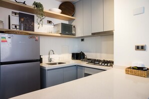 A modern kitchen with a refrigerator, microwave, sink, and stove.