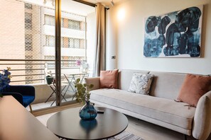 A modern living room with a sofa, a coffee table, and a painting on the wall.