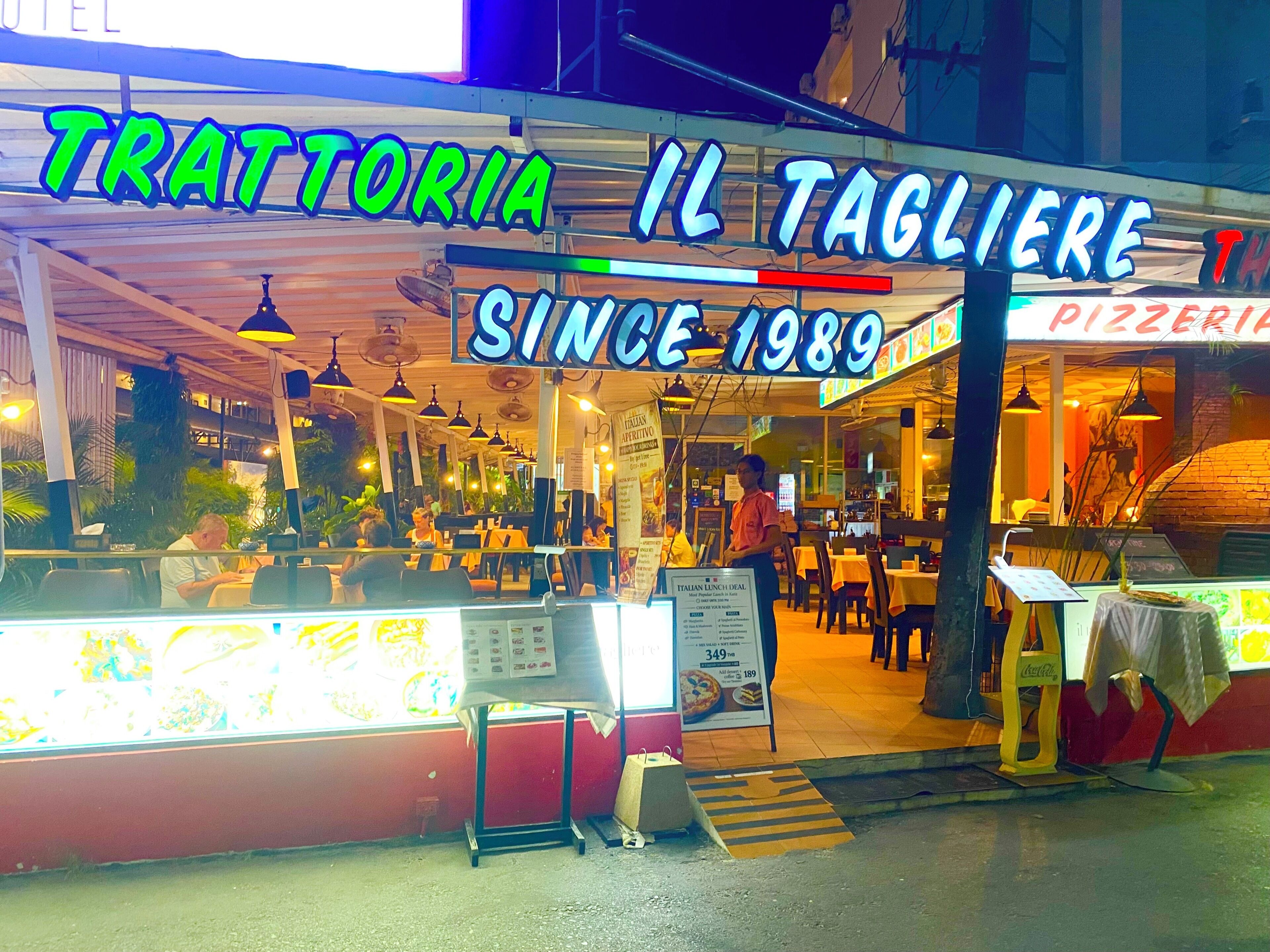 A restaurant named 'Il Tagliere' with a neon sign indicating it has been in business since 1989.