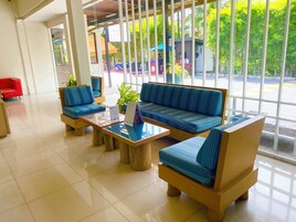 Un vestíbulo con zona de estar, que incluye sofás, sillones, una mesa de centro de vidrio y un mostrador de recepción.