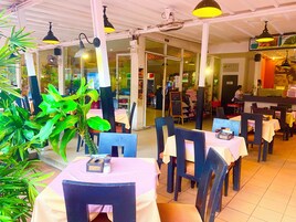 Un restaurante con mesas, sillas y una barra, y una persona al fondo.