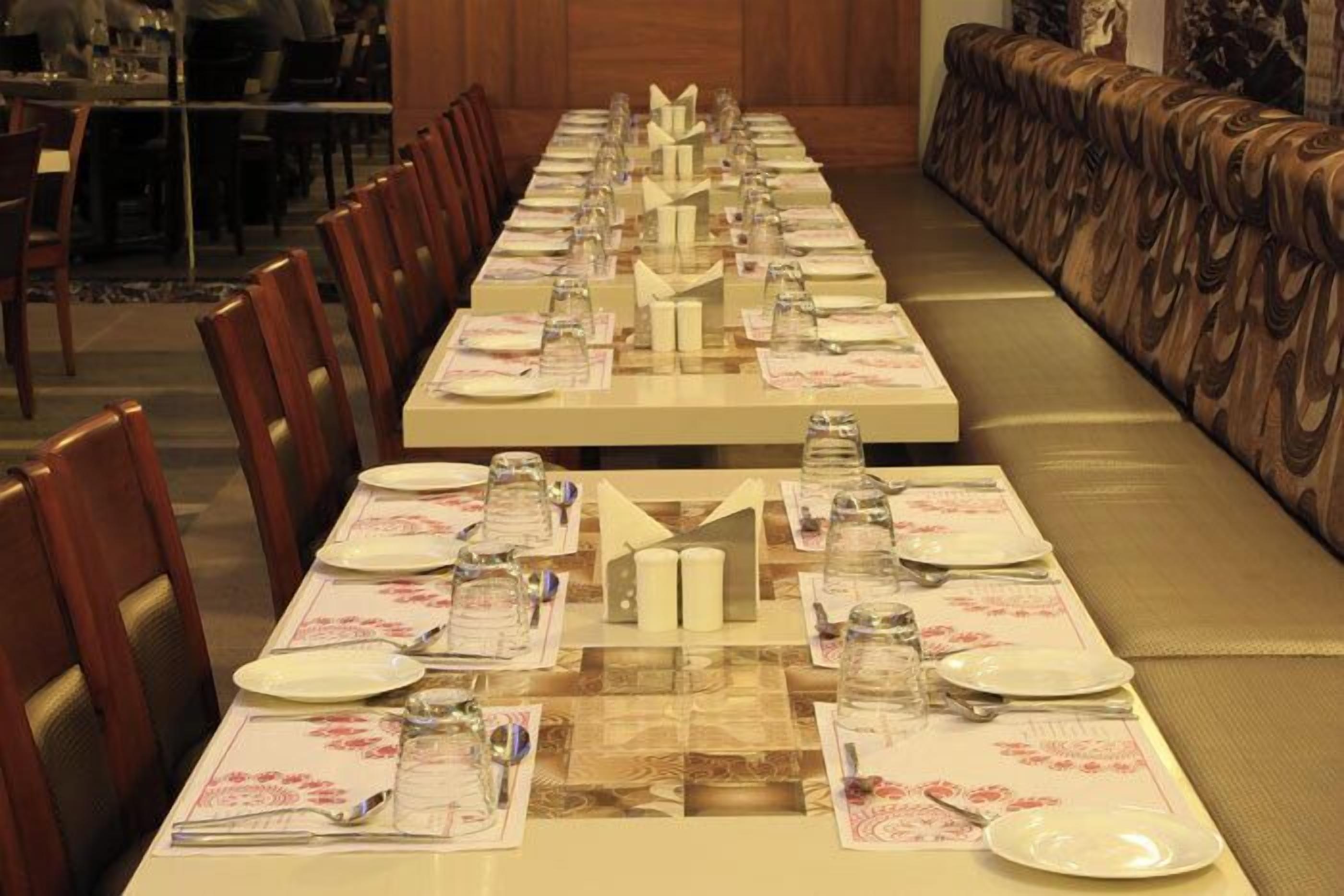 A long dining table set with multiple place settings, including plates, glasses, and cutlery.