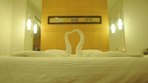 Habitación de hotel con una cama, un cuadro enmarcado en la pared y dos lámparas de pared.