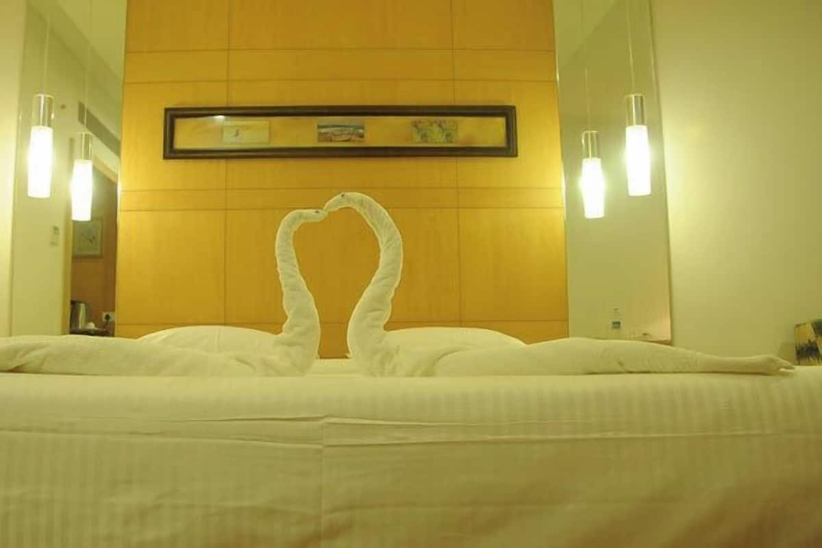 Ett hotellrum med en säng, en inramad tavla på väggen och två vägglampor.