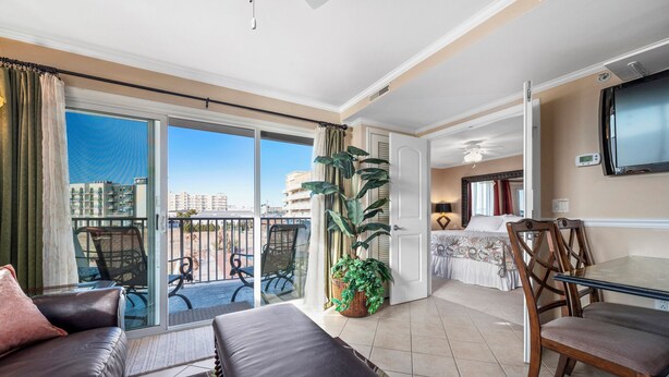Un salon moderne avec balcon, un coin repas et une chambre.