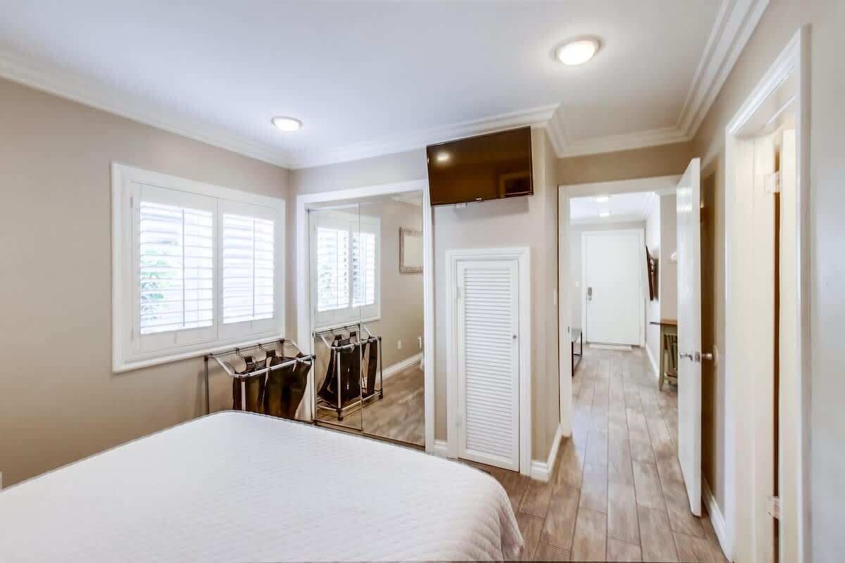 A bedroom with a bed, a wardrobe, a mirror, and a television.
