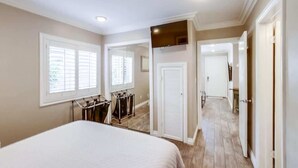 A bedroom with a bed, a wardrobe, a mirror, and a television. - Mission Bay Getaway - Walk to the Water (San Diego)