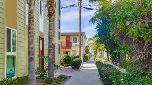 A narrow street lined with buildings, a sidewalk, and lush greenery. - Mission Bay Getaway - Walk to the Water (San Diego)