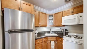 A kitchen with wooden cabinets, stainless steel appliances, a sink, and a stove. - Mission Bay Getaway - Walk to the Water (San Diego)