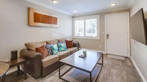 A living room with a sofa, coffee table, and a TV mounted on the wall. - Mission Bay Getaway - Walk to the Water (San Diego)