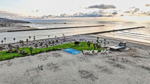 A beach with a lifeguard tower, a parking lot, and a pier in the background. - Mission Beach Gem - 1BR Near the Ocean (San Diego)