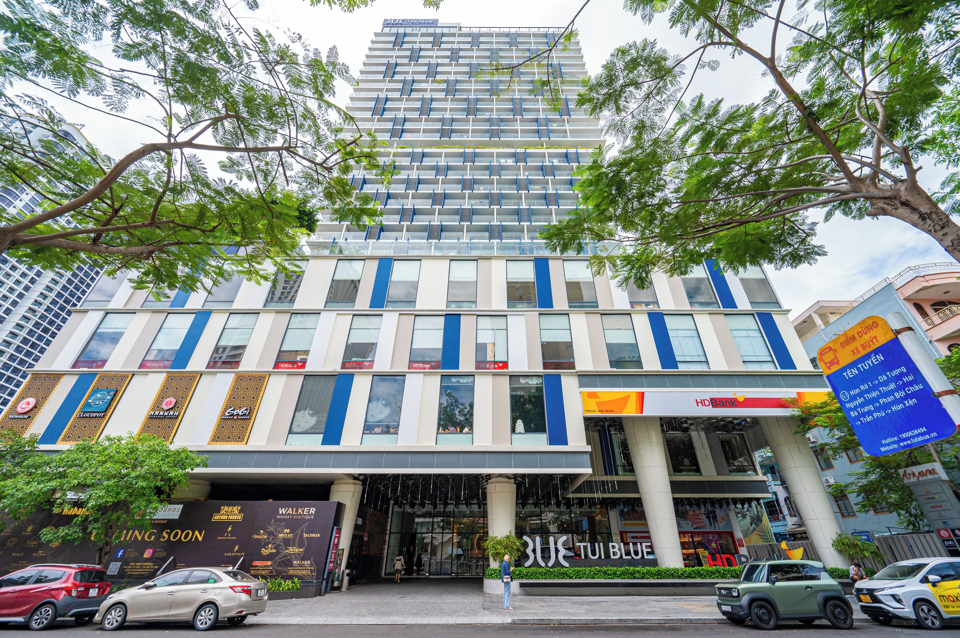 A modern hotel with a glass facade, multiple floors, and a prominent entrance.