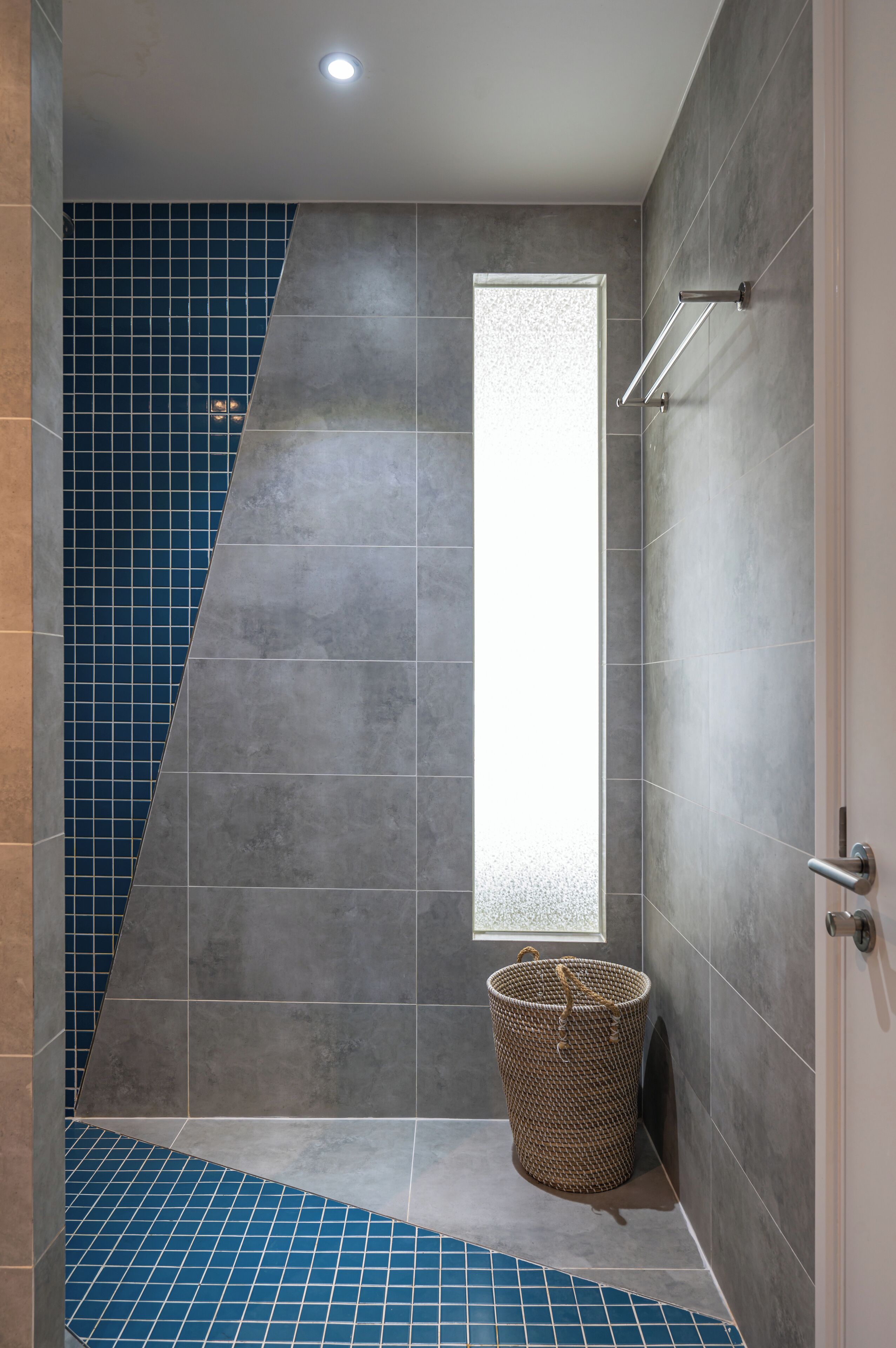 A bathroom with a large window, a shower area, and a tiled floor.