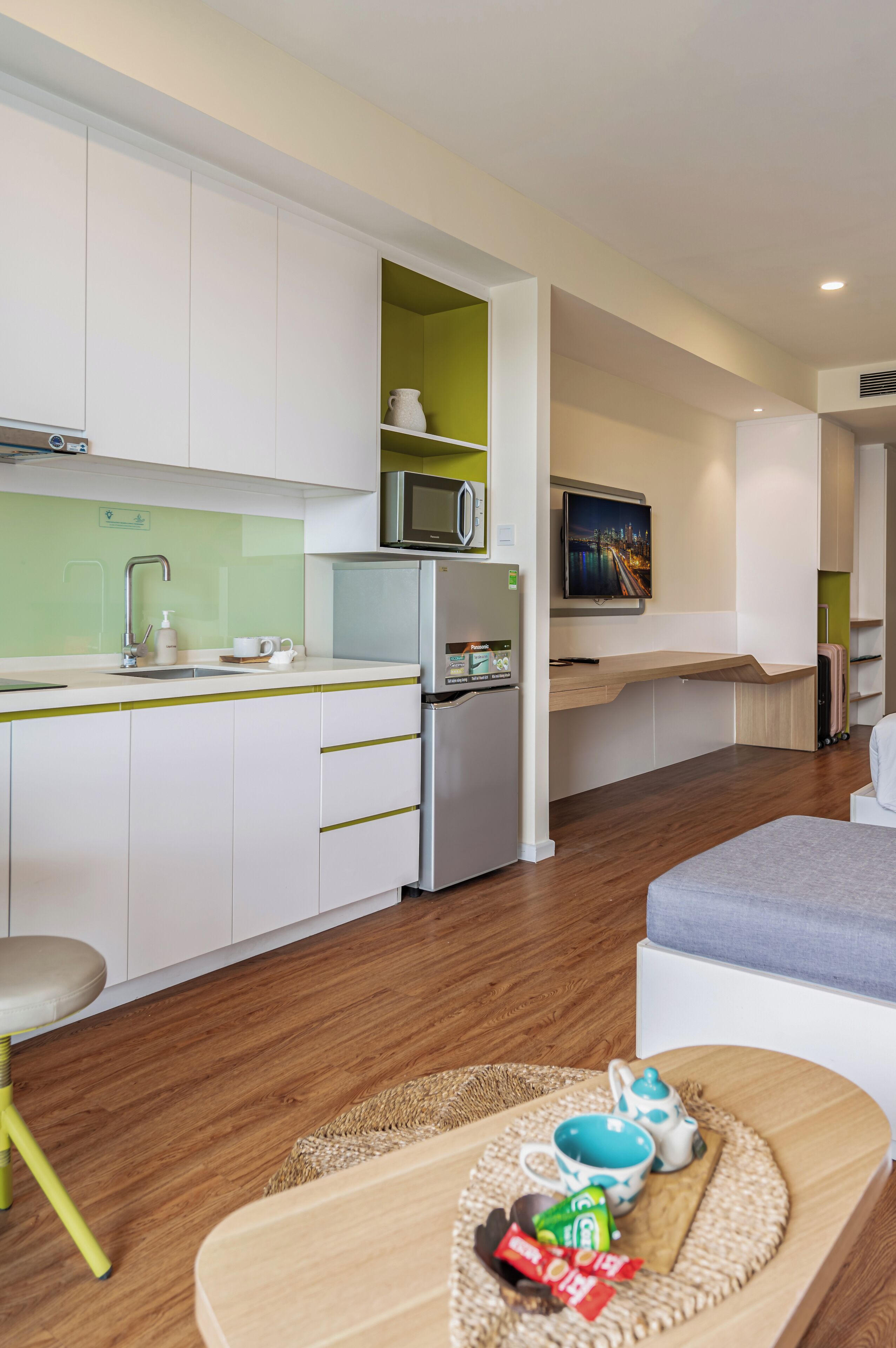 A modern kitchen with white cabinets, a stainless steel refrigerator, a microwave, and a sink.