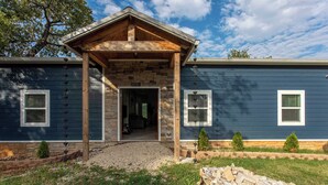 A modern house with a stone facade, a wooden porch, and a gravel driveway.