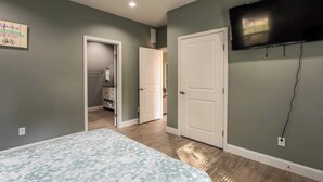 A bedroom with a bed, a TV mounted on the wall, and a door leading to a closet.