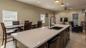 A modern kitchen with a central island, dining area, and seating.