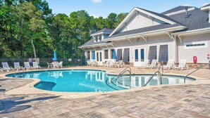 A swimming pool with lounge chairs and a covered patio area.