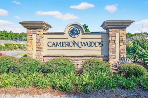 A sign for Cameron Woods with a stone arch and a tree logo. - 4BR Townhouse with Golf View in Ocean Isle Beach (Ocean Isle Beach)