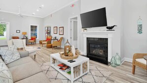 A living room with a fireplace, a flat-screen TV, and a cozy seating area with a sofa and chairs.