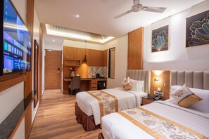 A hotel room with two beds, a desk, and a TV.