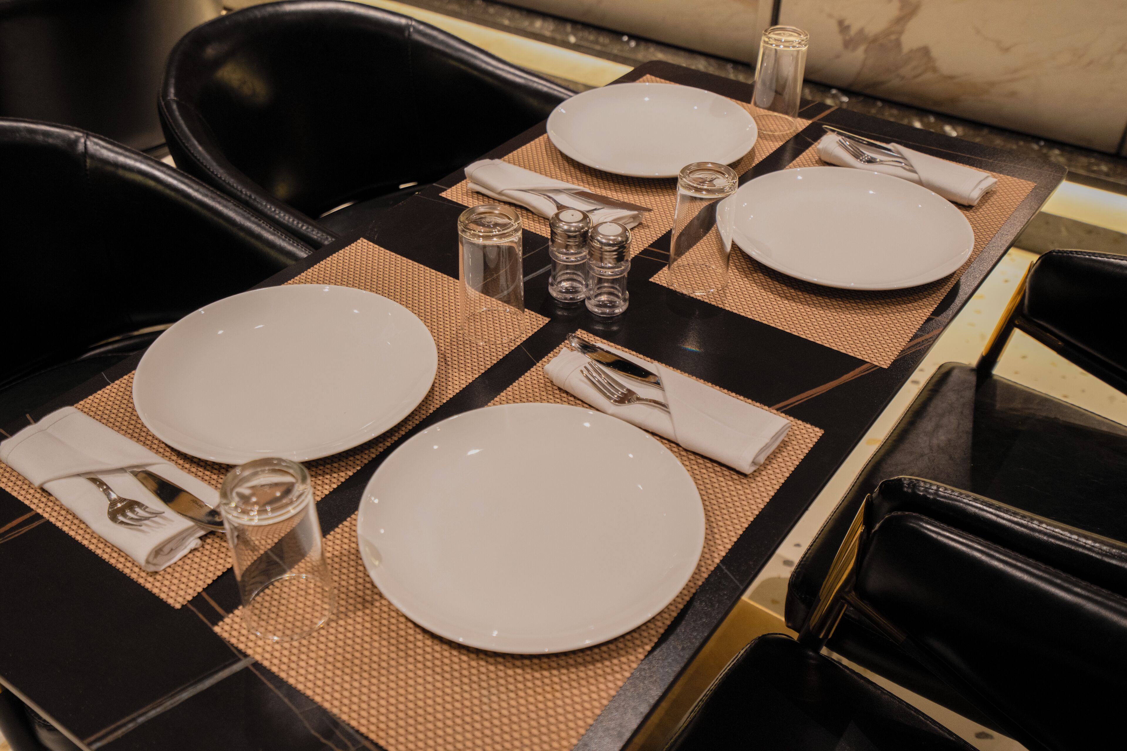 A dining table set with plates, cutlery, and salt and pepper shakers.