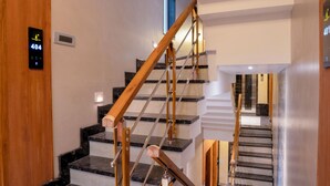 Un interior moderno con una escalera que presenta un barandal de madera y peldaños de mármol negro.