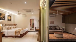 Una habitación de hotel con una cama, un sofá, una mesa de centro redonda y un espejo.