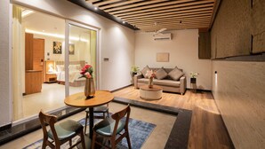 Una habitación de hotel moderna con techo de madera, una mesa redonda con sillas, un sofá y una mesa de centro.