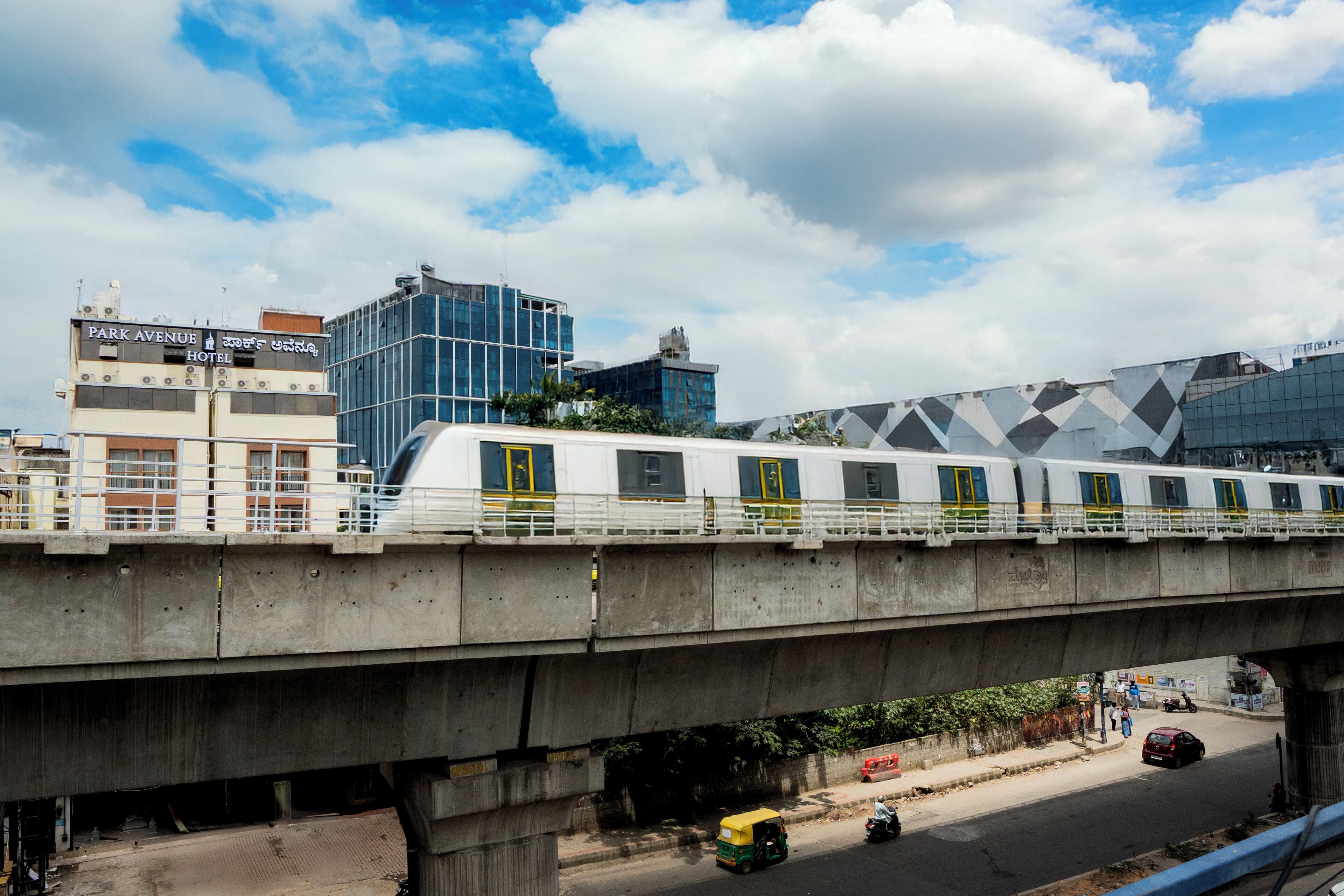 A train on an elevated track with a hotel in the background.